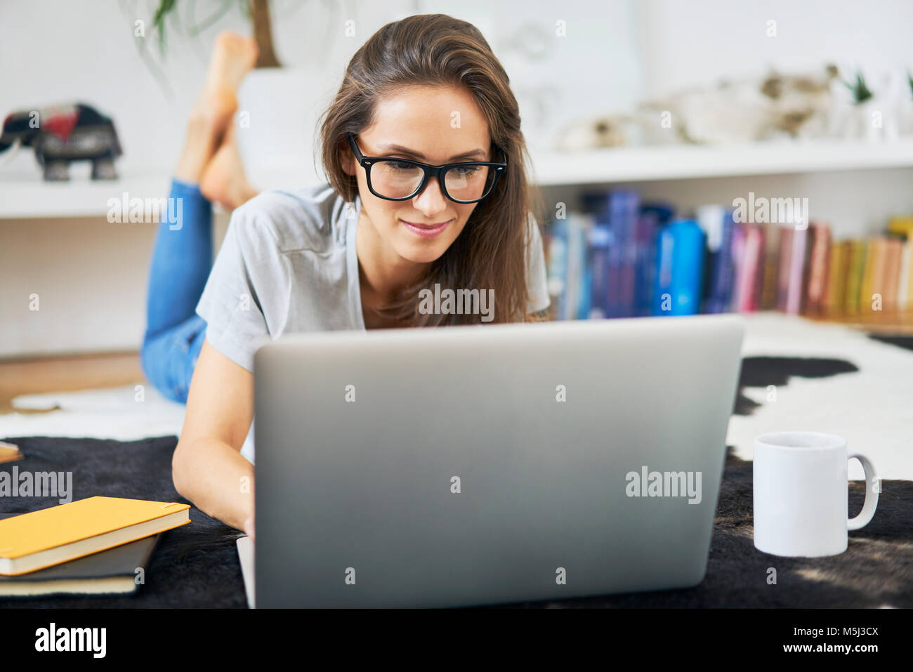 Young woman at home lying on the floor using laptop Stock Photo - Alamy