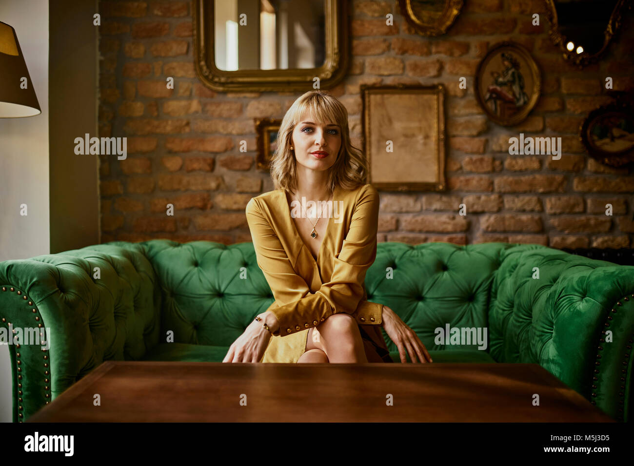 Portrait of elegant woman sitting on a couch Stock Photo - Alamy
