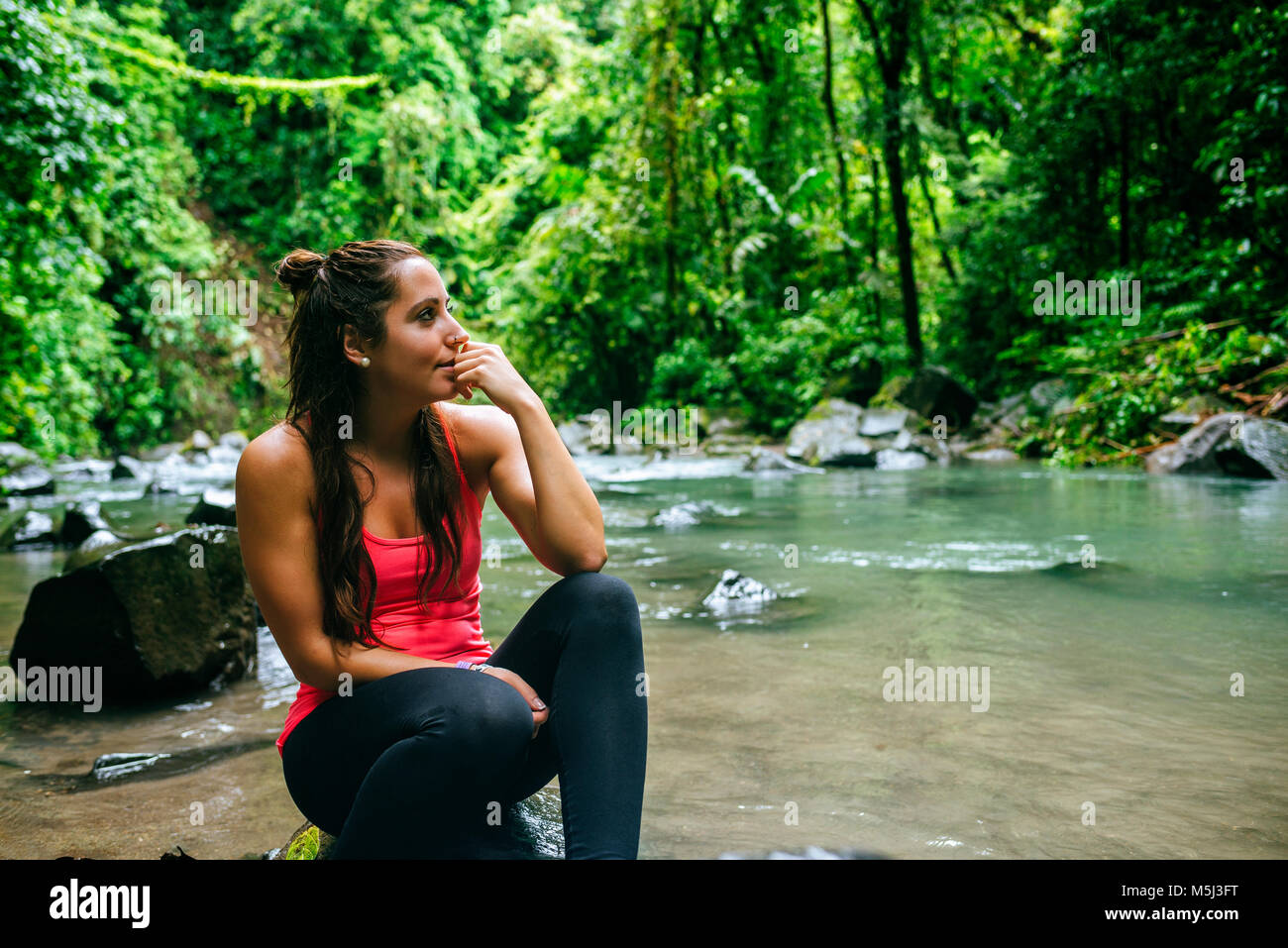Costa Rica, Arenal Volcano National Park, Woman sitting on a stone of the river Fortuna Stock Photo