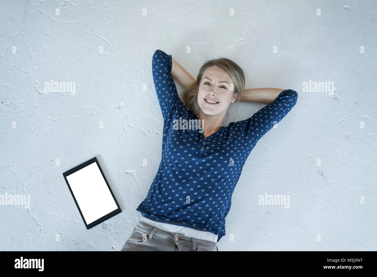Portrait of smiling young woman lying on the floor with tablet Stock Photo