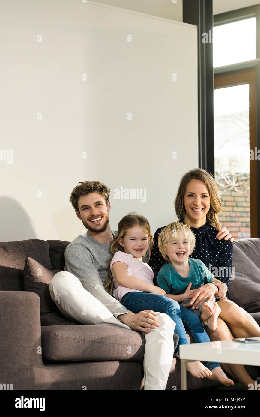 Portrait of happy family sitting on sofa at home Stock Photo