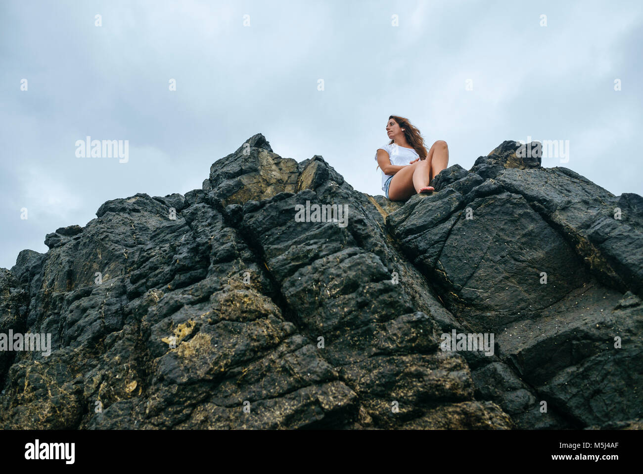 Costa Rica, Woman sitting on rocks, view from below Stock Photo