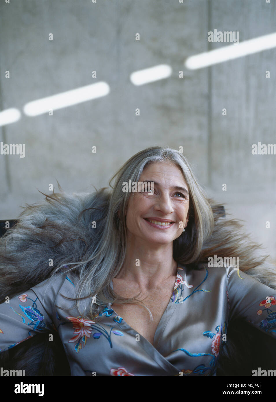 Portrait of laughing mature woman sitting in armchair Stock Photo - Alamy