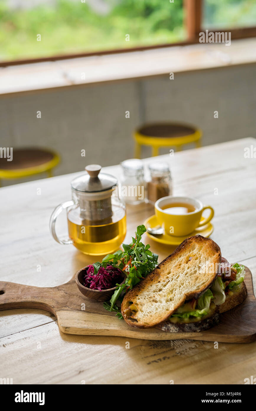Crusty bread with green salad and beetroot on wooden plate and green tea in cafe Stock Photo
