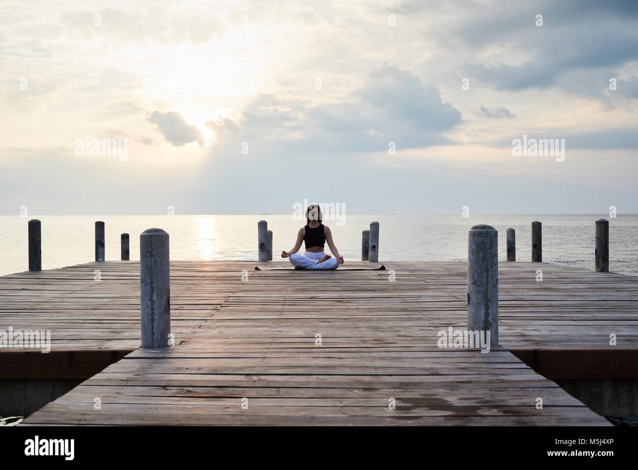 Yoga instructor practicing meditation in a lotus position against sunset and sea. Kep, Cambodia. Stock Photo