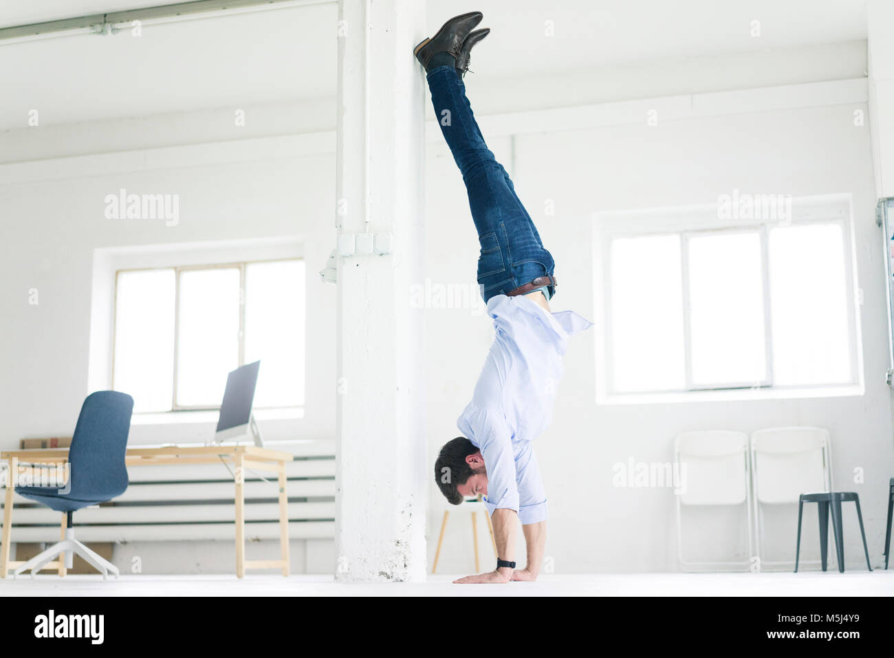 Businessman doing a handstand in office Stock Photo