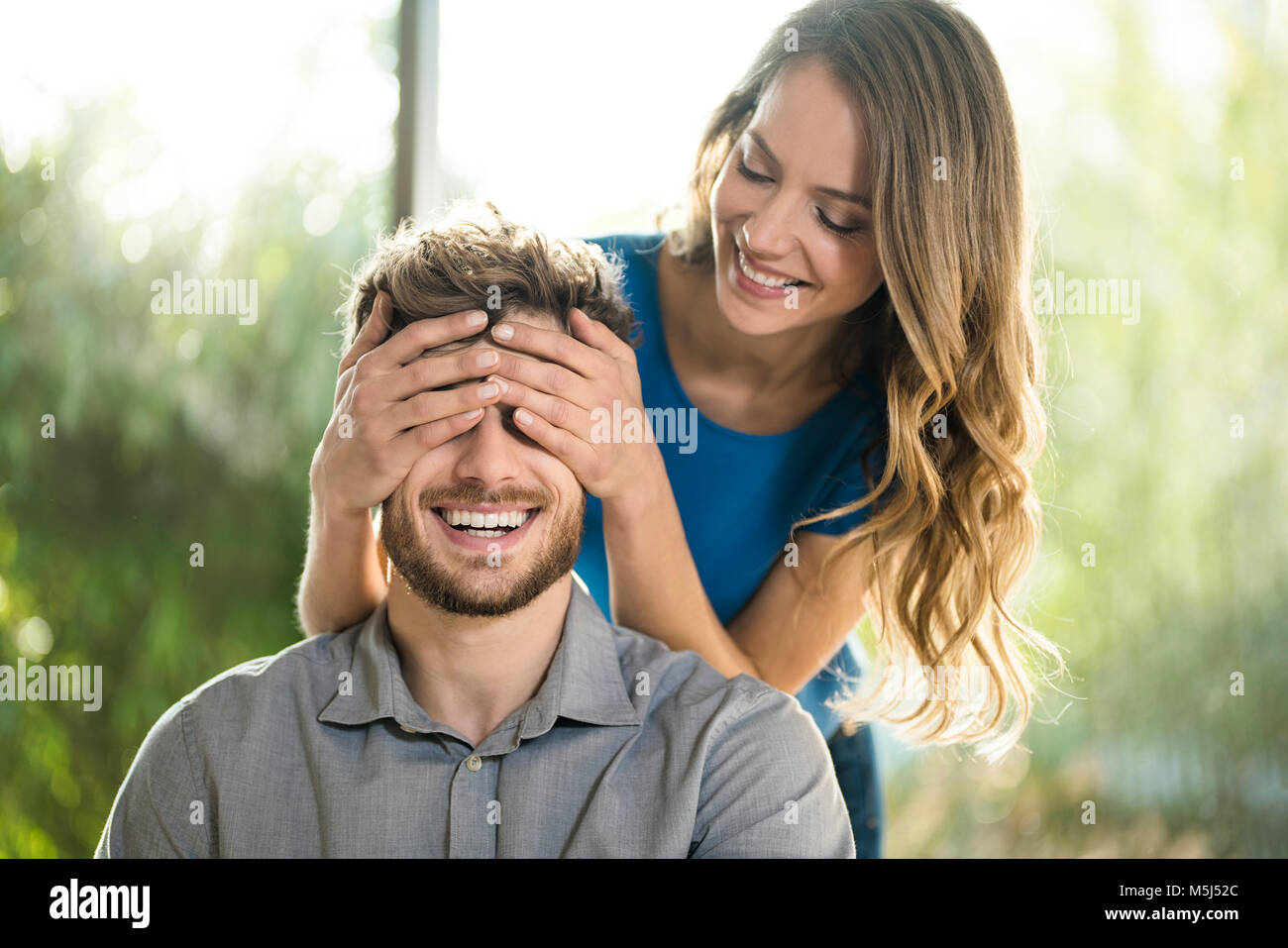 Smiling woman covering her boyfriend's eyes Stock Photo