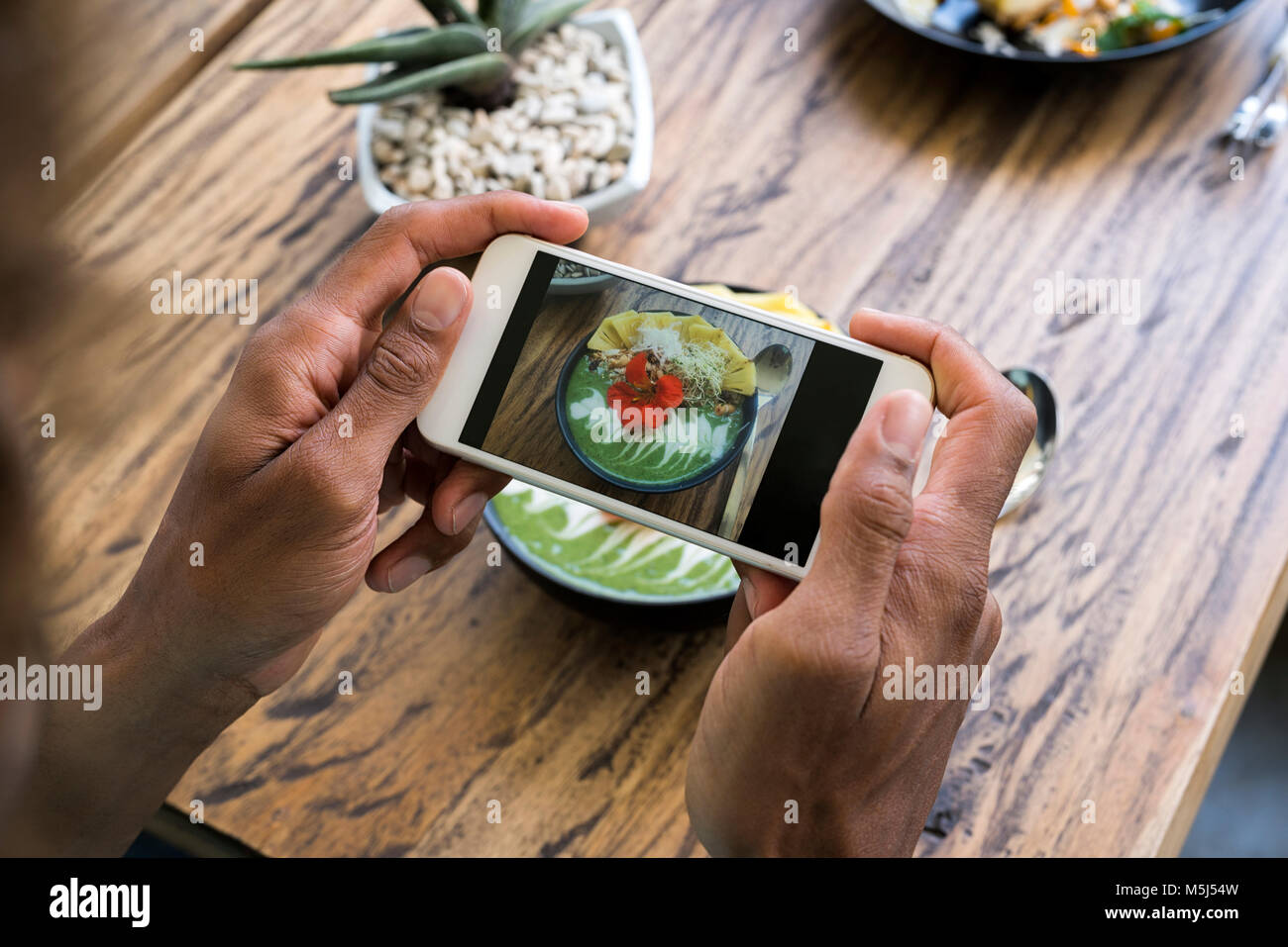 Male hands taking a picture of smoothie bowl with smartphone Stock Photo