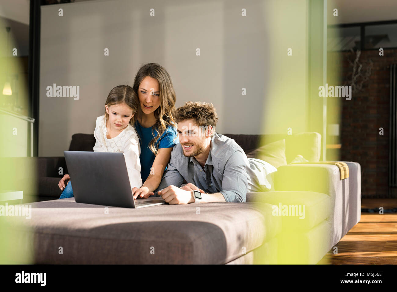 Family using laptop on sofa at home Stock Photo