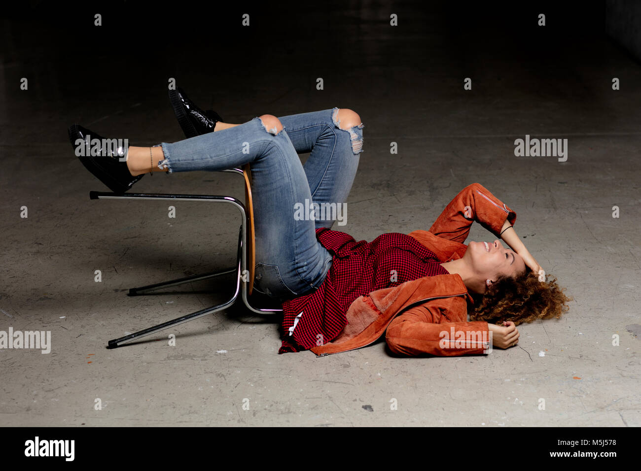 Laughing woman lying on the floor with chair Stock Photo - Alamy