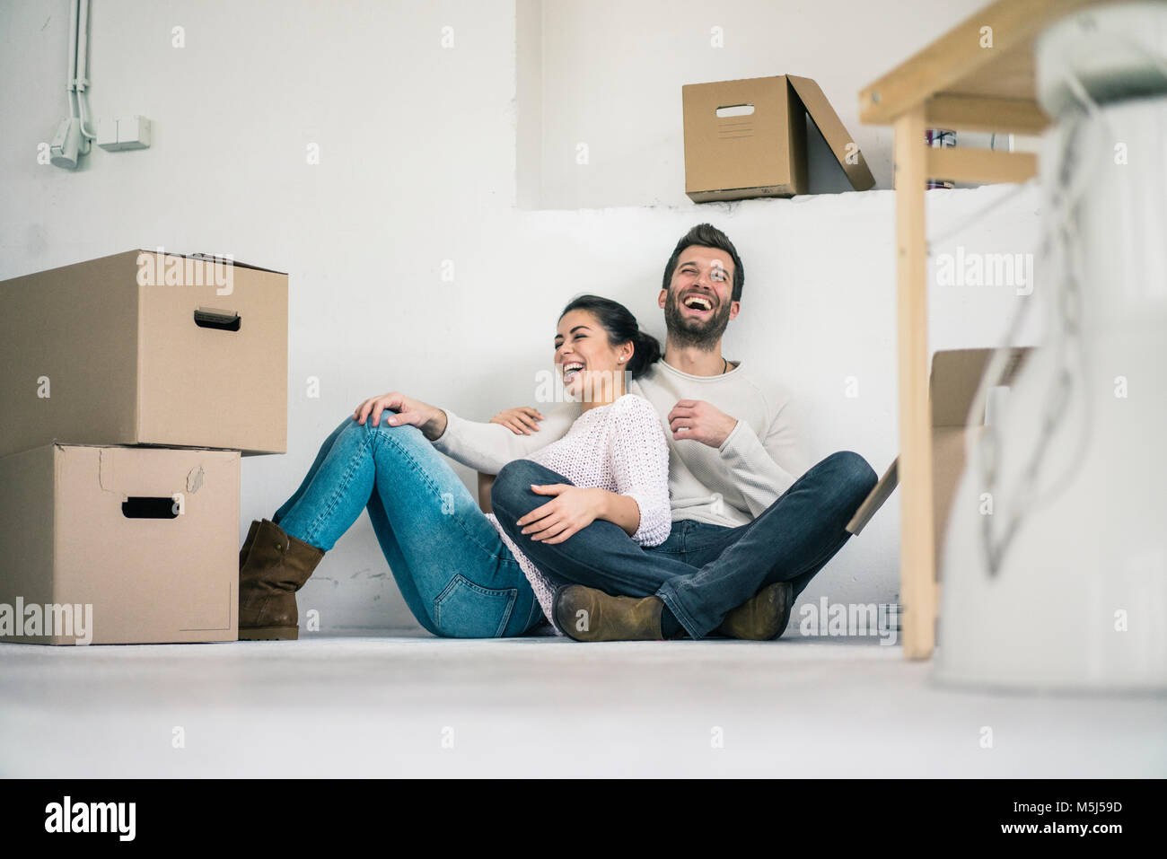 Laughing couple sitting in new home surrounded by cardboard boxes Stock ...
