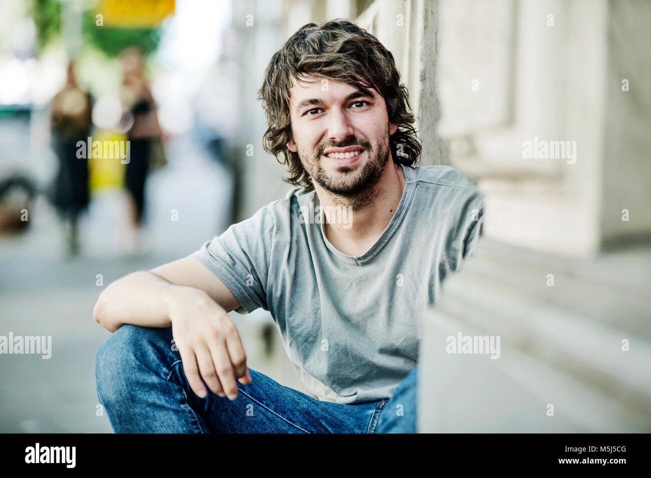 Portrait of smiling young man sitting outdoors Stock Photo - Alamy
