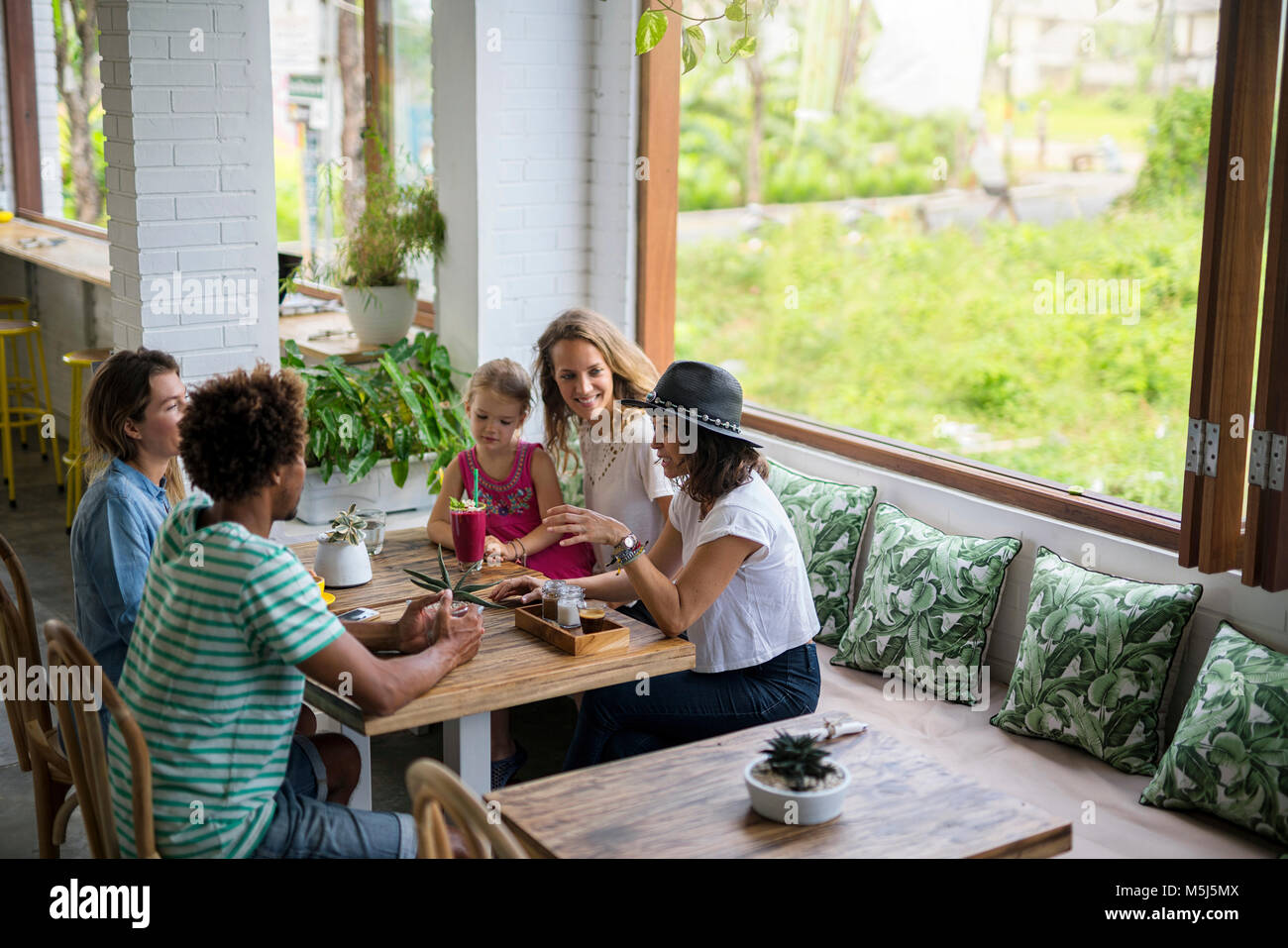 Friends with child socializing in cozy cafe Stock Photo