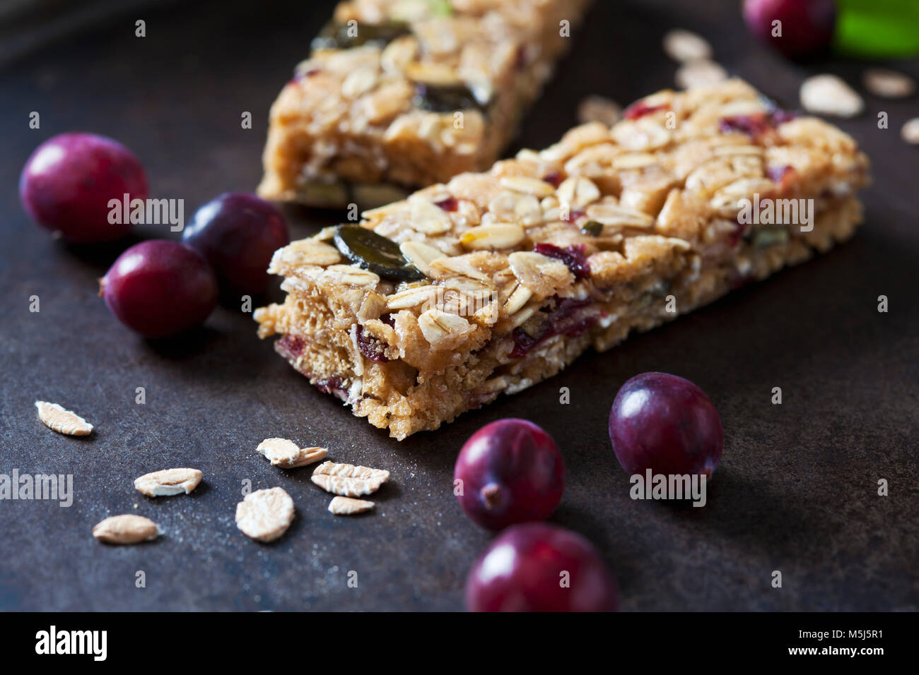 Muesli bars with cranberries and oat flakes on dark background Stock Photo