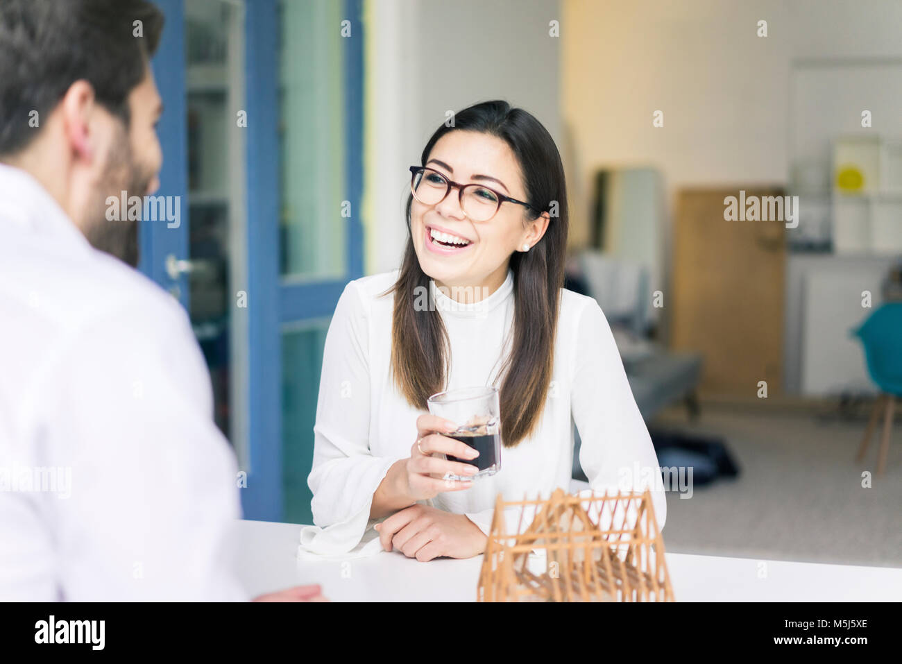 Woman laughing at man with architectural model on table Stock Photo