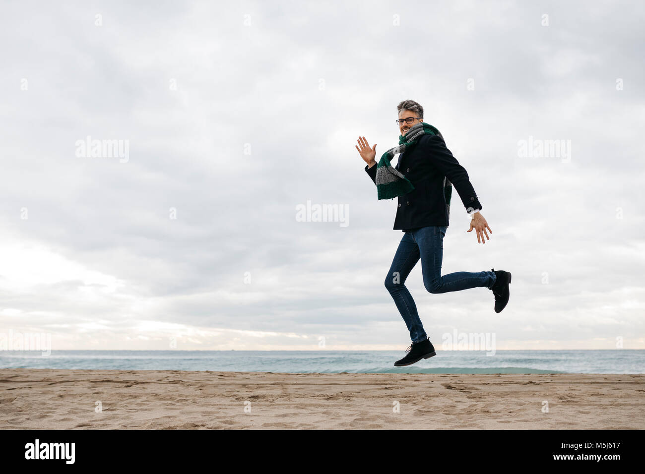 Man jumping on the beach in winter Stock Photo