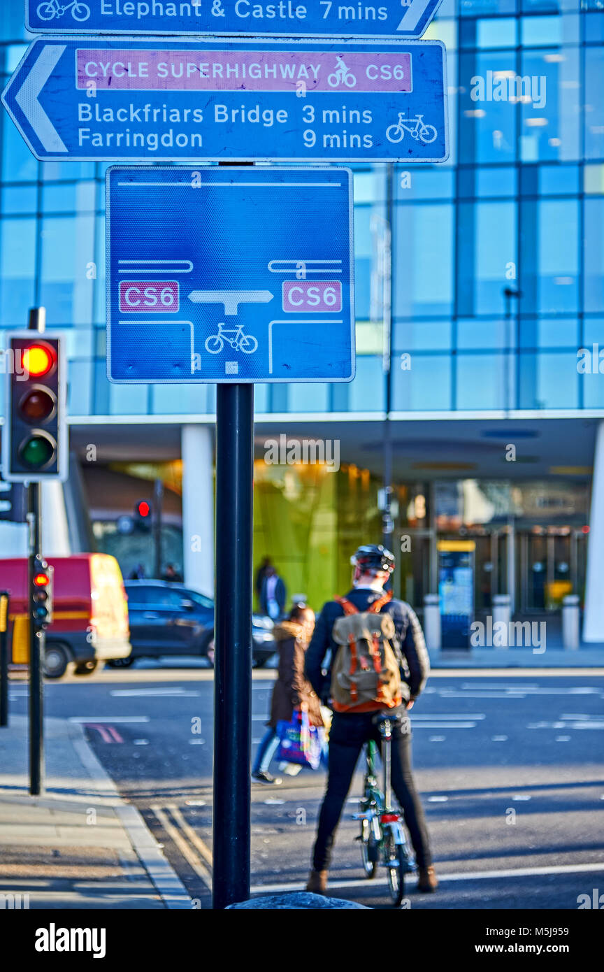A man riding a Brompton folding bicycle waiting at a red traffic light to join Cycle Superhighway 6 in Southwark, London Stock Photo