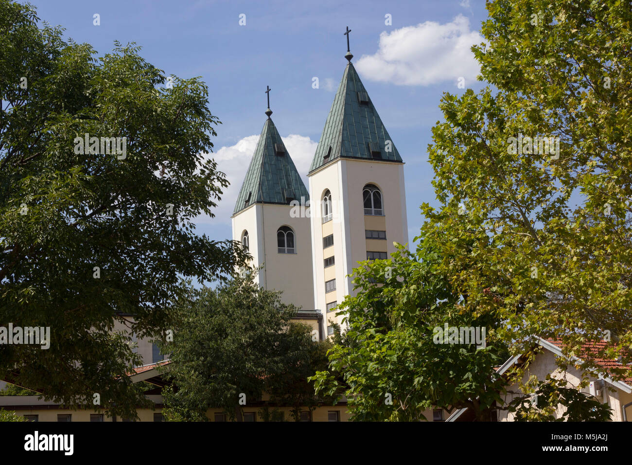 MEDJUGORJE - BOSNIA AND HERZEGOVINA - AUGUST 16 2017: Saint James belfries in Medjugorje, surrounded by nature in summer season Stock Photo