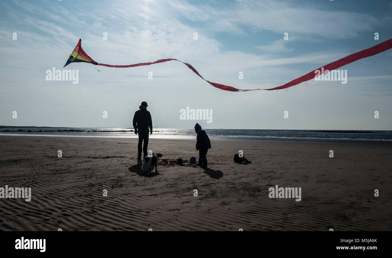 A father and son flying a kite on a deserted beach at Seamill, Scotland. Stock Photo