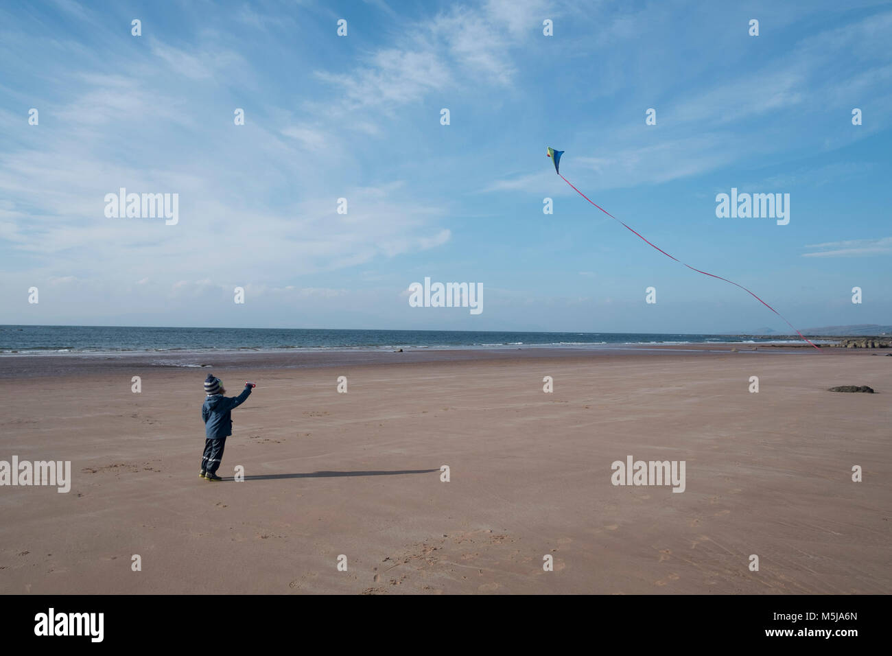 A young boy flying his kite on the beach at Seamill, Scotland. Stock Photo