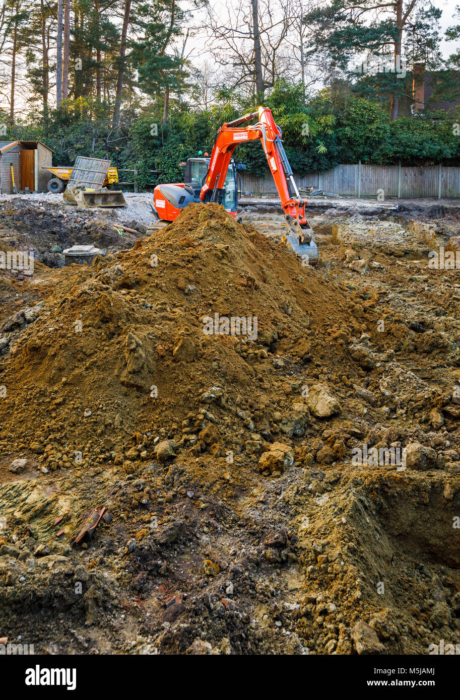 Large orange heavy plant mechanical digger parked on a construction site after digging excavations for foundations of a new residential development Stock Photo