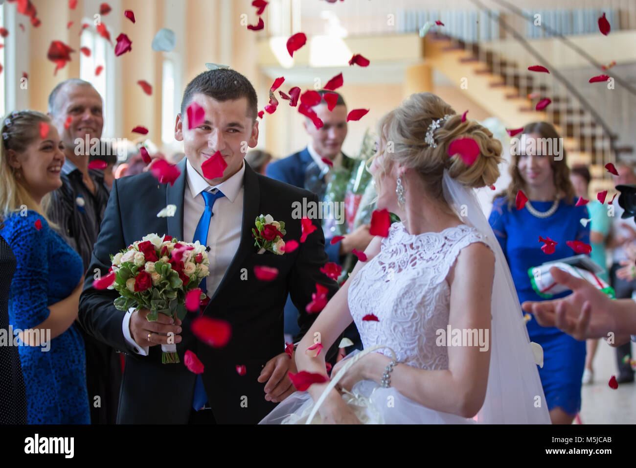 on the bride and groom throw rose petals. Bride and groom happy in rose petals Stock Photo