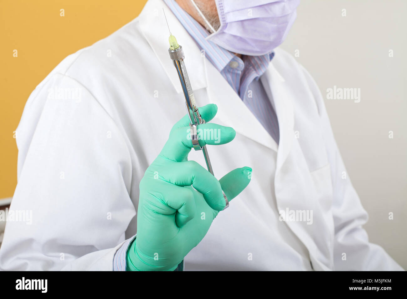 Male dentist with mask holding local anesthetic injection preparing for