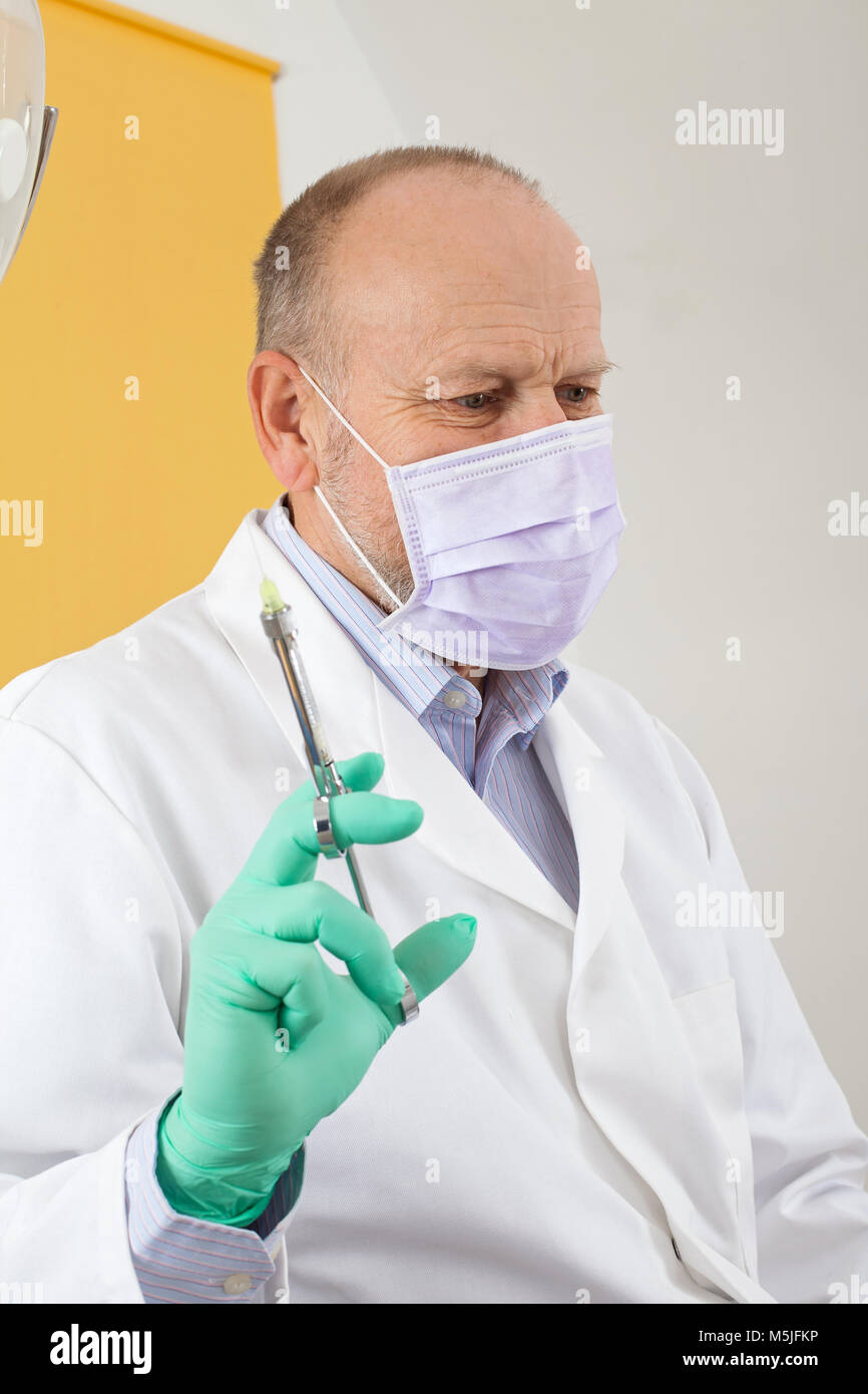 Male dentist with mask holding  local anesthetic injection preparing for treatment Stock Photo