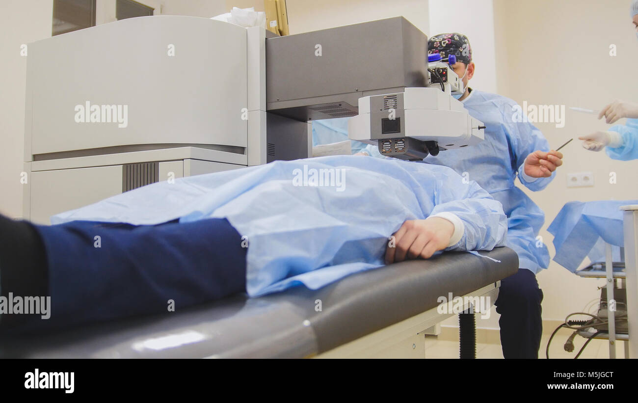 The patient lies on the operating surgical table during ophthalmology operation surgery wthout anesthesia - laser vision correction Stock Photo