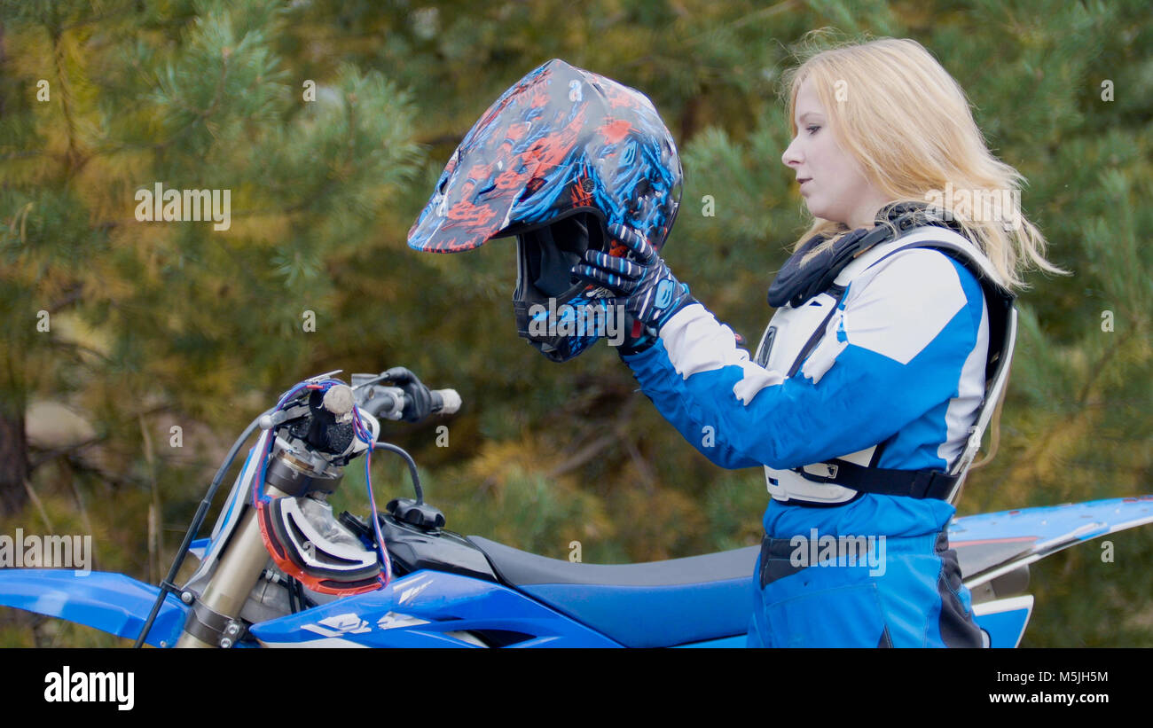 Blonde young Girl Bike wears a helmet - MX moto cross racing - rider on a dirt motorcycle Stock Photo