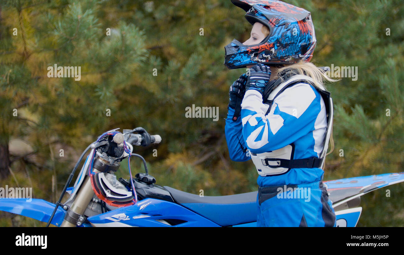 Girl Bike wears a helmet - MX moto cross racing - rider on a dirt motorcycle Stock Photo