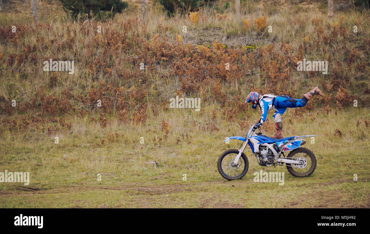 MX moto woman Biker shows acrobatic at cross racing - rider on a dirt motorcycle Stock Photo