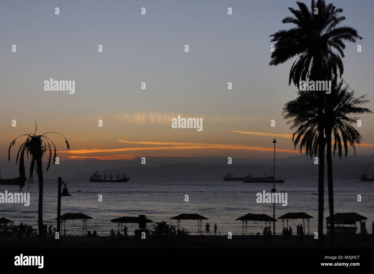 Sunset on a beach in Aqaba bay with big vessels in the background, Aqaba, Jordan Stock Photo