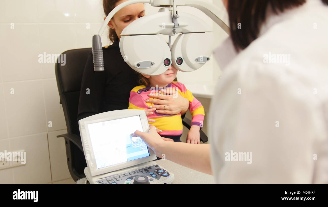 Cute little girl with mommy at the ophthalmologist on consultation Stock Photo