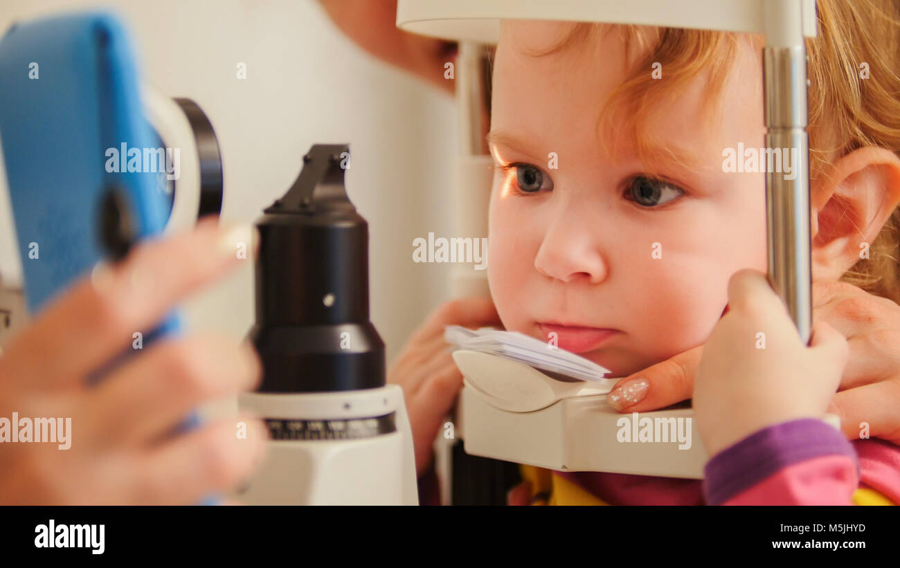 Child's optometry - little girl checks eyesight in eye ophthalmological clinic - close up Stock Photo