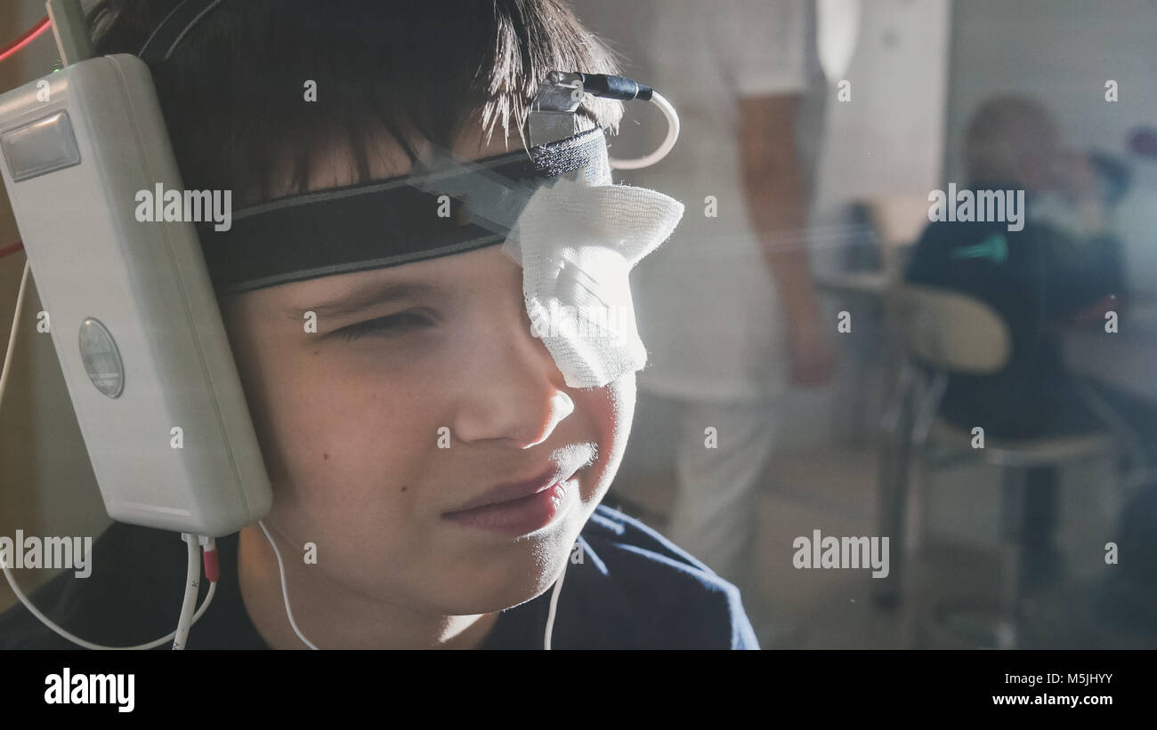 Boy with electrodes on the head looking to monitor - healthcare children's diagnostic - Ophthalmology researching Stock Photo