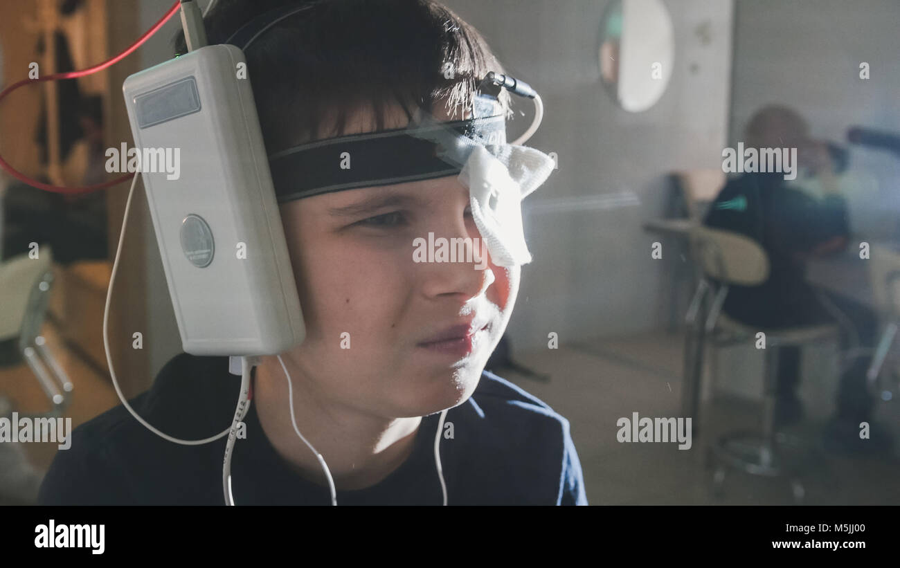 Teenager boy with electrodes on the head looking to monitor - healthcare children's diagnostic - Ophthalmology researching Stock Photo