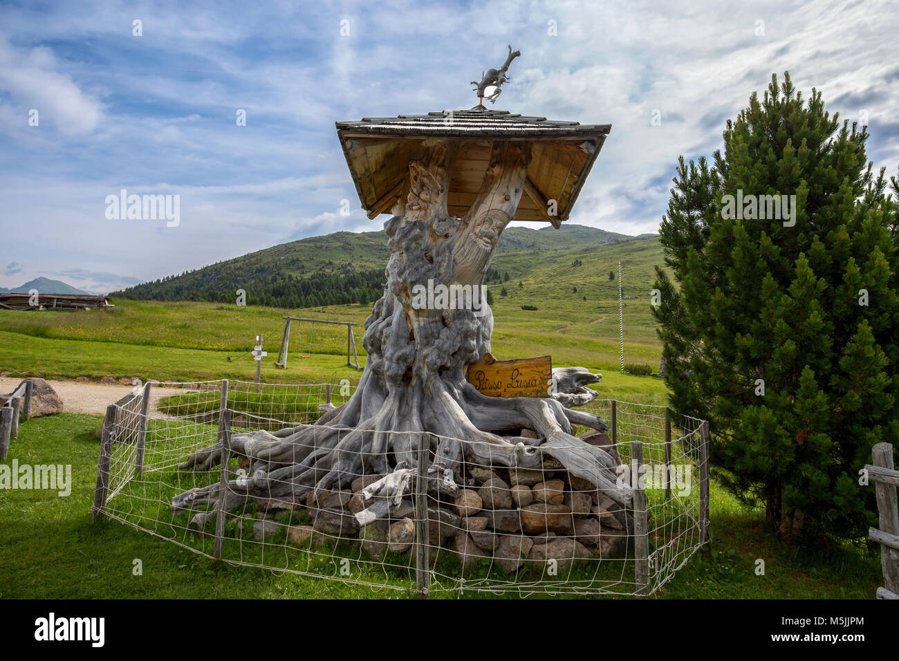 Wooden sculpture carved from a tree in a mountain landscape / Dolomites
