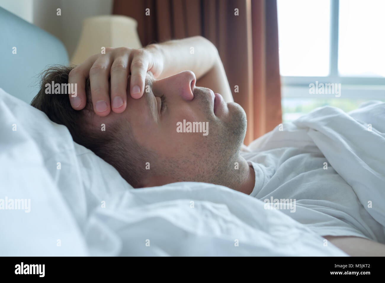 man lying in bed at home suffering from headache or hangover Stock Photo