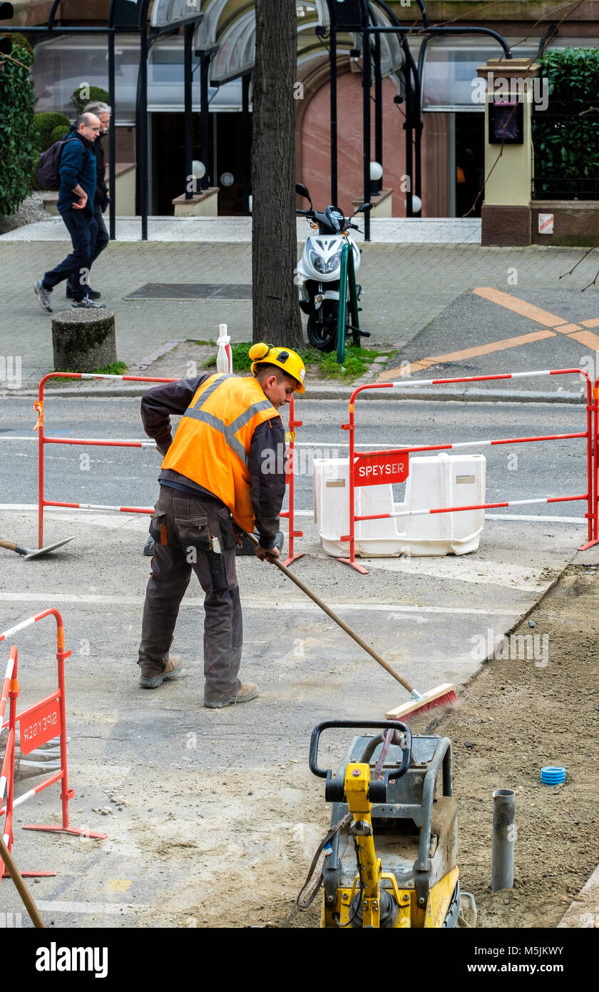 Civil engineering Strasbourg, worker sweeping service trench, urban