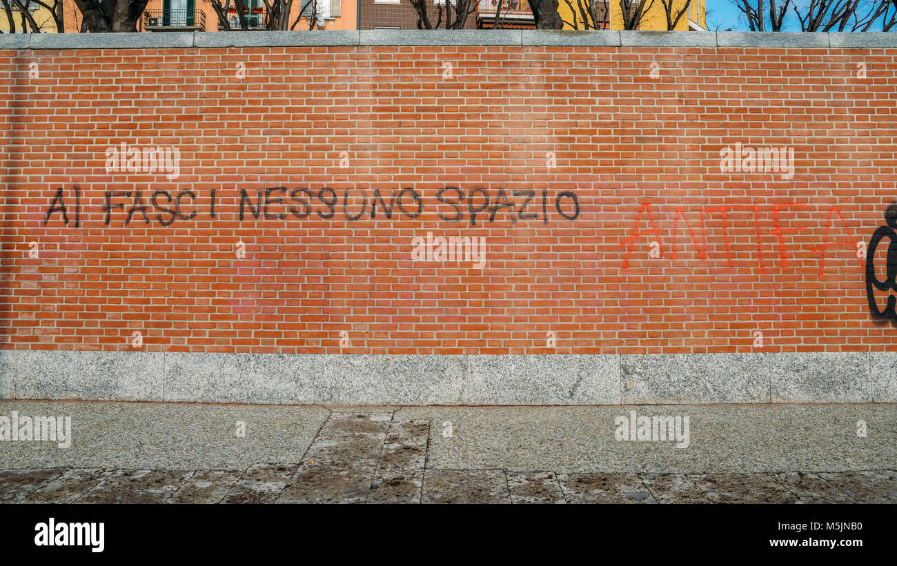 Milan, Italy - Feb 24, 2018: Graffiti on a red brick wall in Italian saying al fasci nessuno spazio, translated to no room for fascists - antifa theme Stock Photo