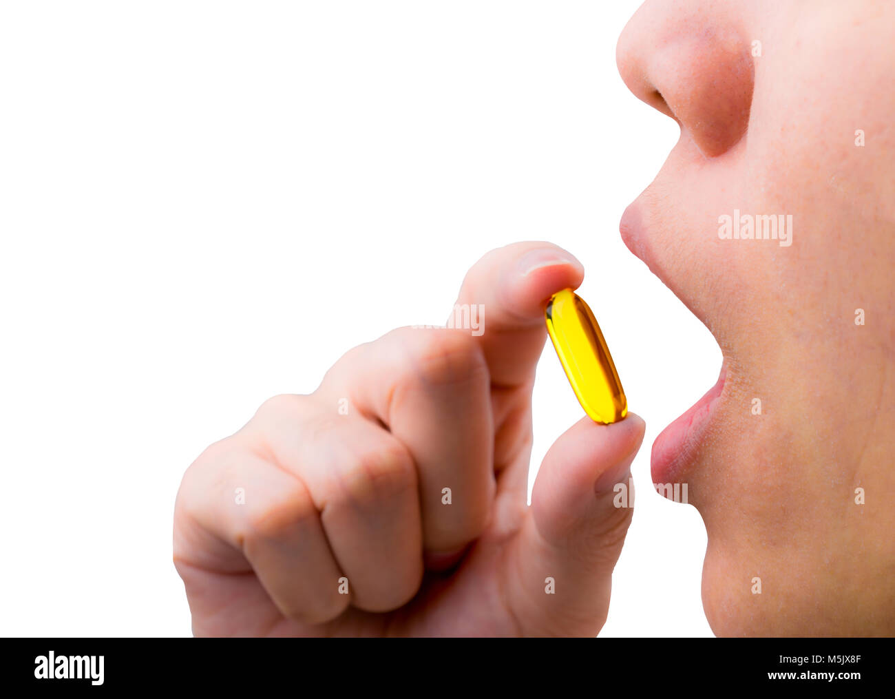 Young woman hand hold fish oil capsule near open mouth. Woman taking