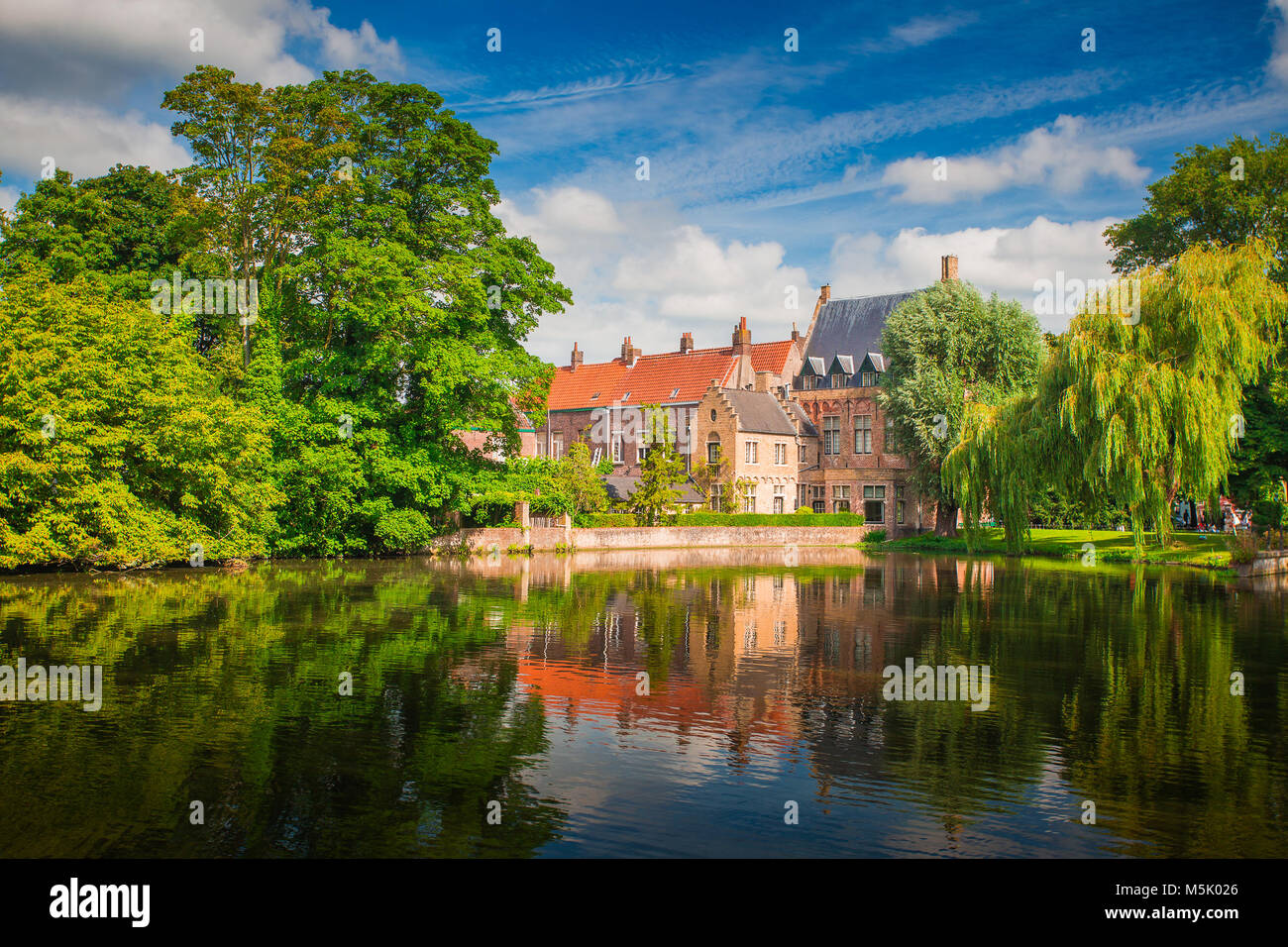 Sunny Brugge cityscape. Buildings of Bruges reflected in lake. Historical center of Europe. Stock Photo