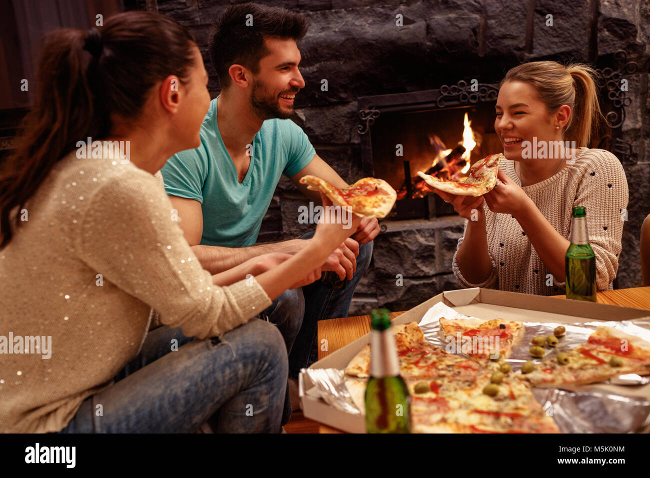 smiling friends having fun time together at home and eating pizza Stock Photo