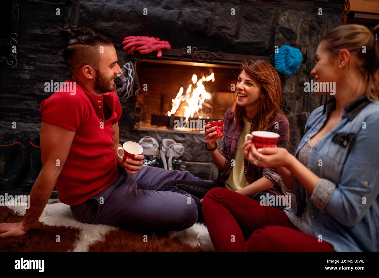 friend's relaxation after skiing in front of fireplace at home Stock Photo