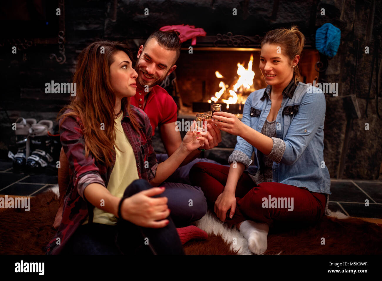 Time of relaxing after skiing- Happy friends cheering with drinks together Stock Photo