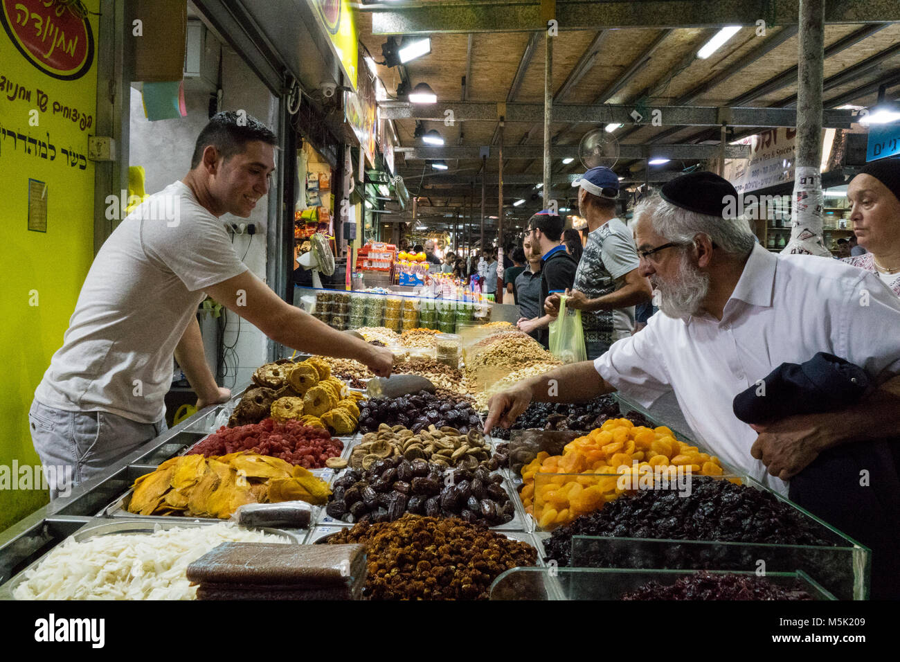 A man asking about dates on a driet fruits and nuts stall at the Mahane Yehuda Market at Jerusalem. Stock Photo