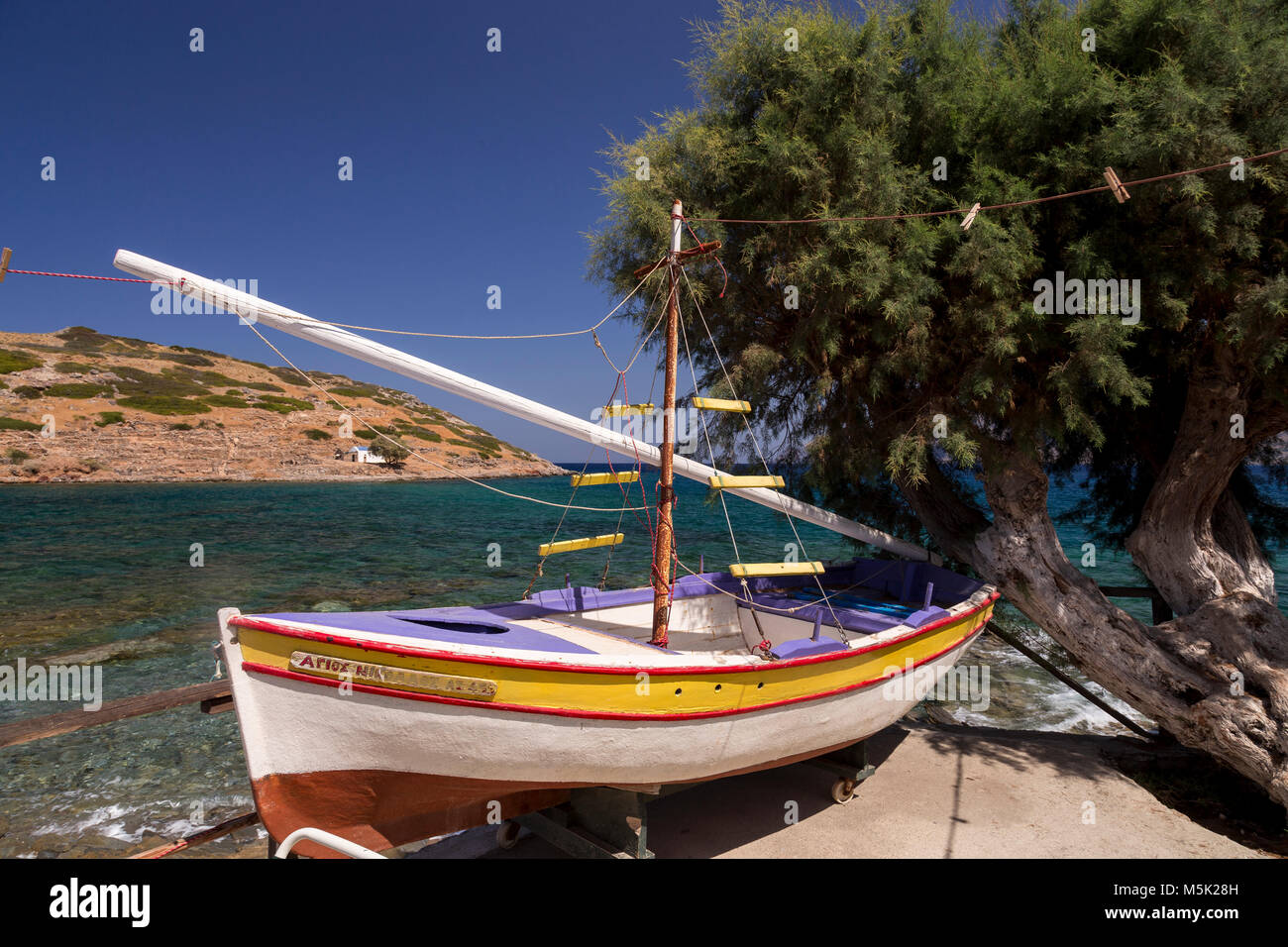 Boat and tree on the sea wall at Mochlos, Crete in the Mediterranean Stock Photo