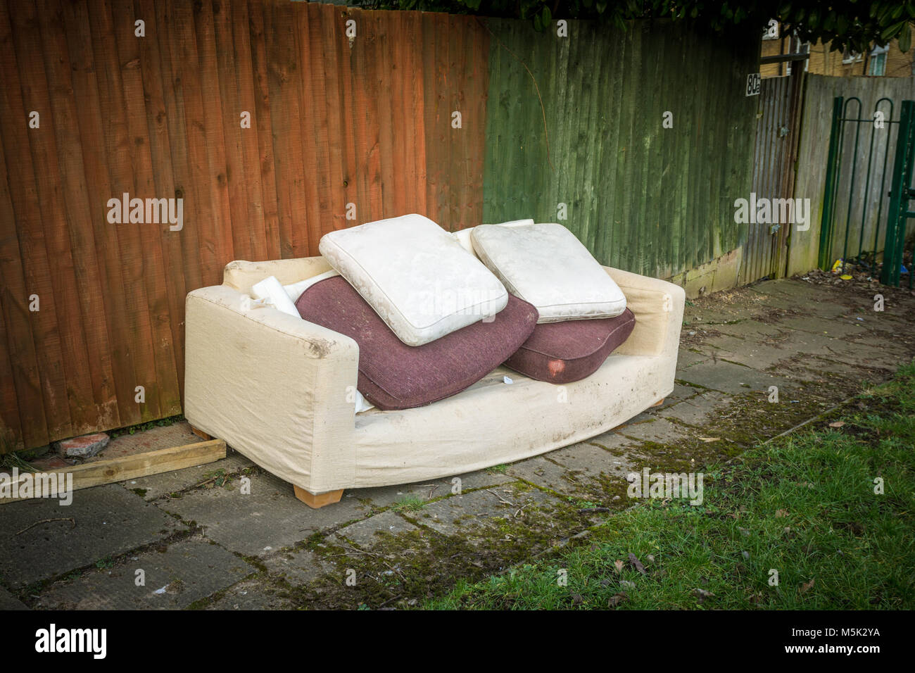 Old sofa dumped or fly tipped outside on a council estate uk Stock Photo