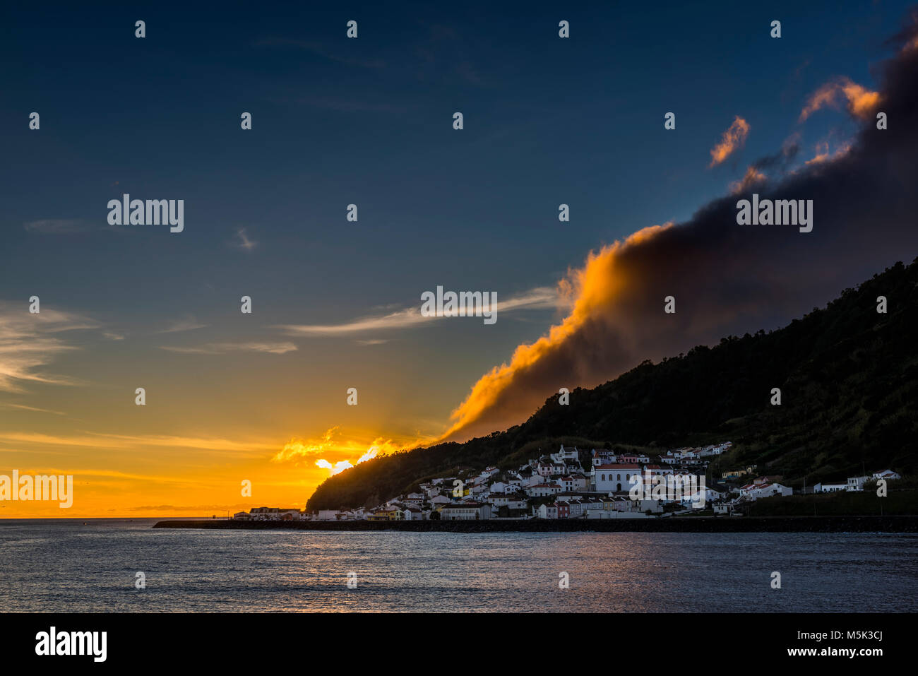 Small village by the sea, sunset with dramatic clouds behind mountain ridges, Ribeira Quente, Sao Miguel, Azores, Portugal Stock Photo